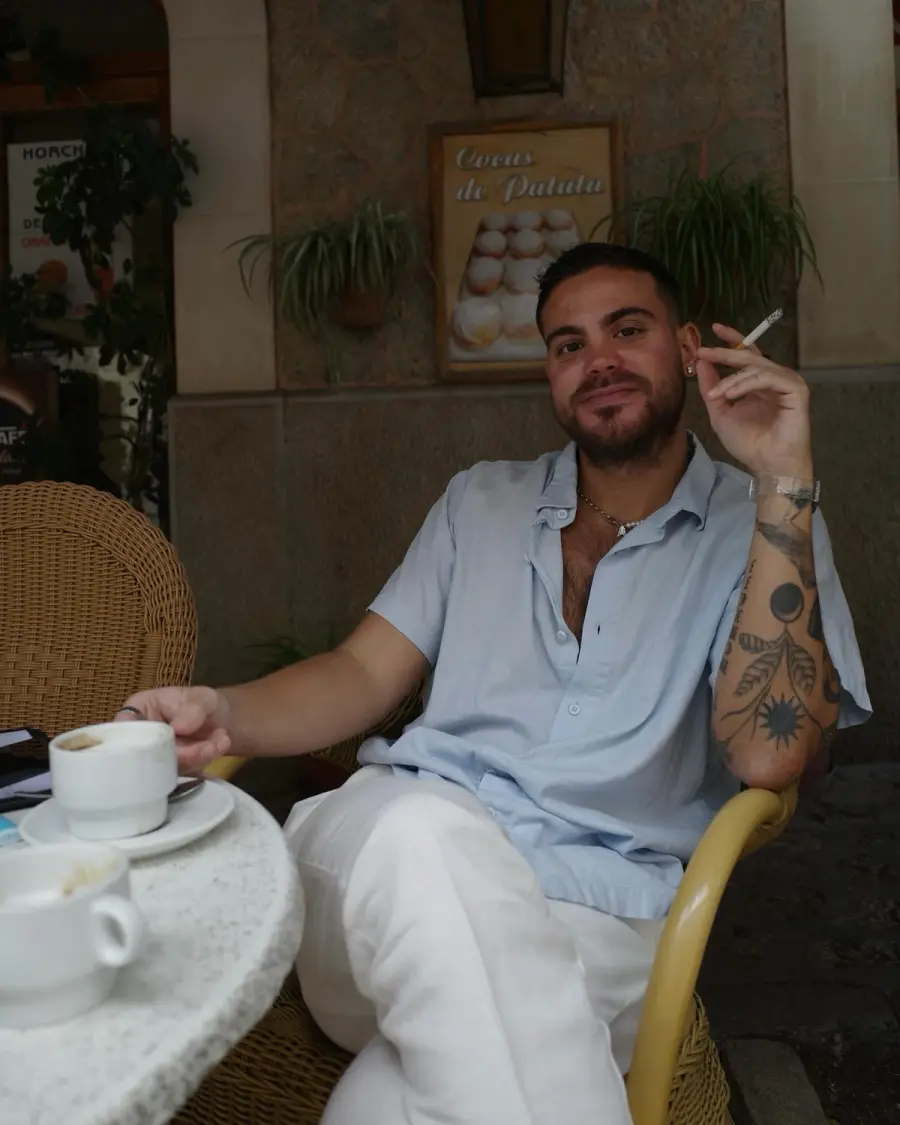 Pedro relaxing in a wicker chair at a café table with coffee cups