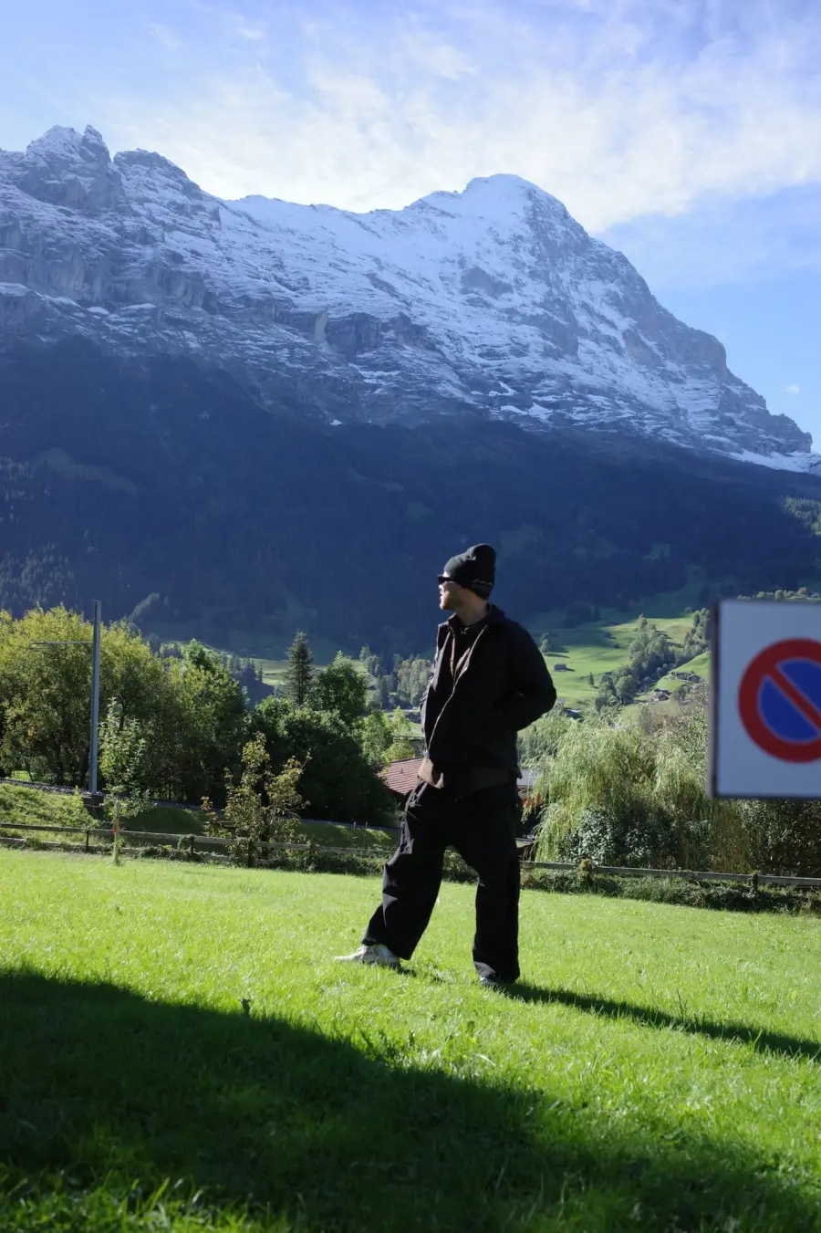 Pedro on a sunny meadow below a snow-dusted mountain face