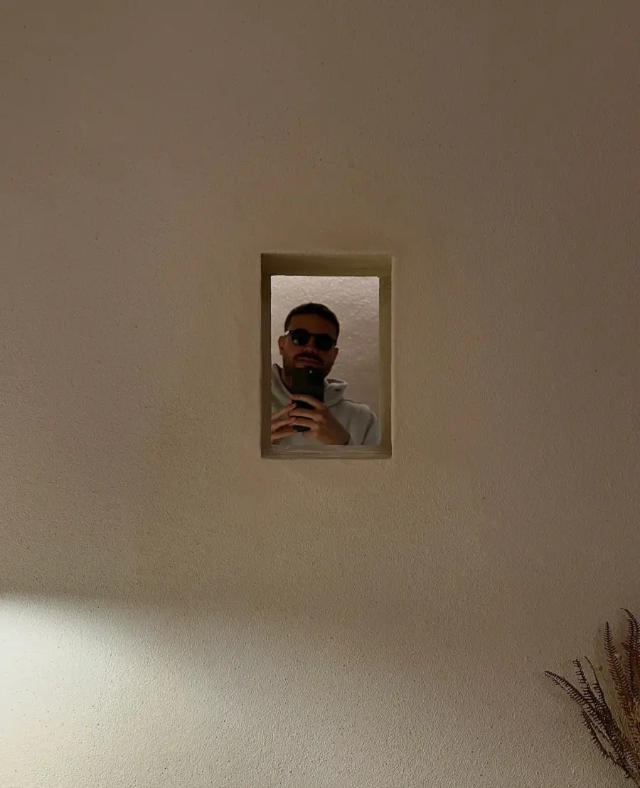 Pedro's selfie in a small mirror set into a plaster wall